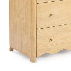 Close-up of a light maple three-drawer wooden dresser with round brass knobs, scalloped base and tapered legs, modern minimalist bedroom nightstand