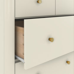 Close-up of cream modern dresser with partially open drawers, gold cone knobs, exposed wooden drawer interior and metal glide — bedroom storage furniture