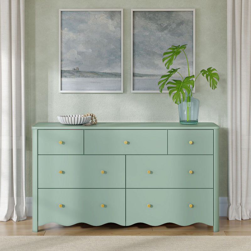 Mint green dresser with yellow knobs in modern interior, framed coastal abstract art, monstera plant in glass vase and neutral curtains