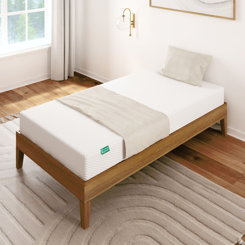 Single memory foam mattress on a wooden bed frame in a bright bedroom.