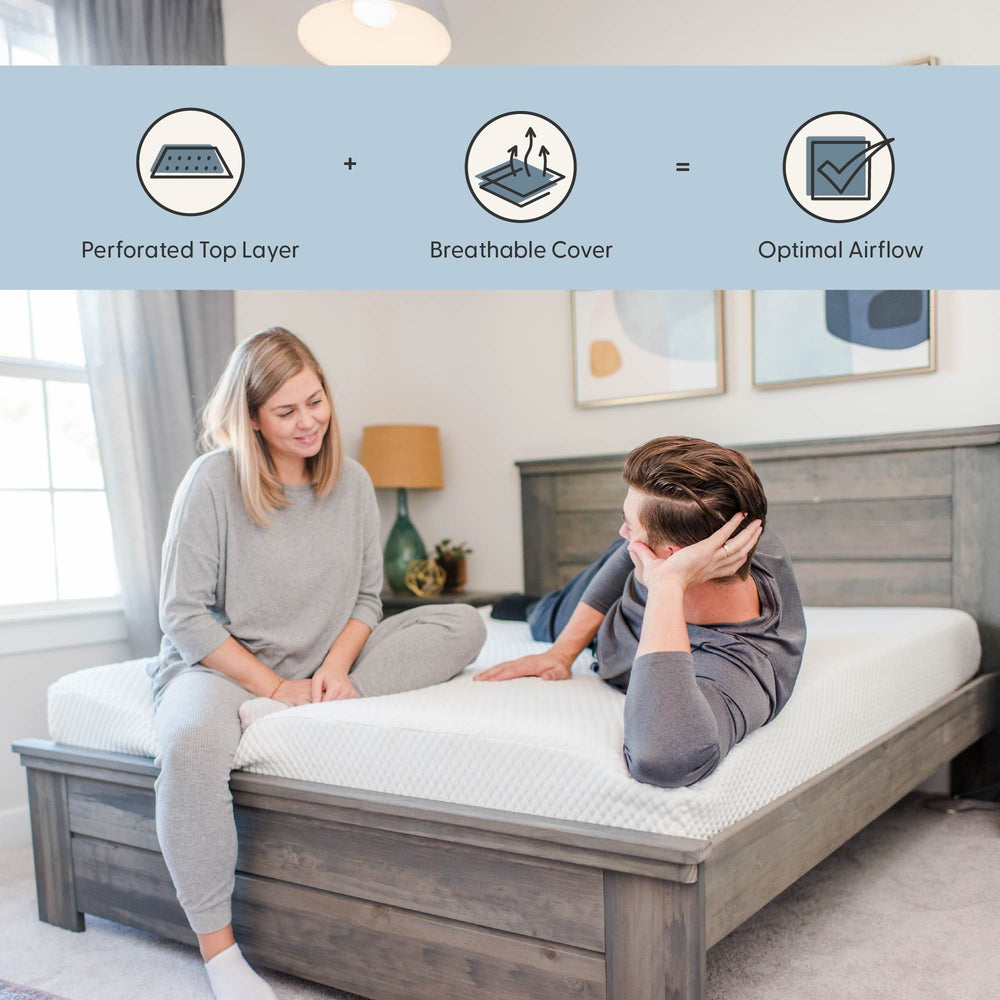 Couple sitting on a comfortable mattress with perforated top layer and breathable cover for optimal airflow in a modern bedroom.