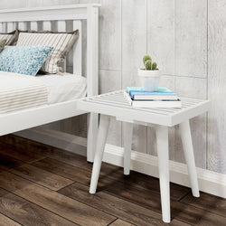 White wooden bedside table with potted cactus and books next to modern bed in cozy bedroom.