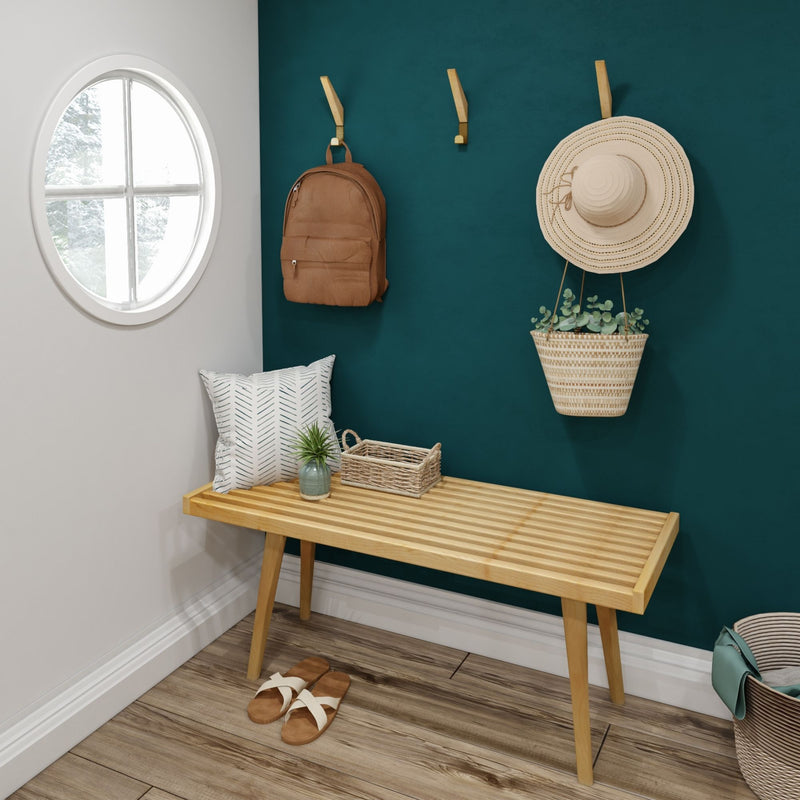 Cozy entryway with wooden bench, green wall, wicker basket, and hanging backpack.