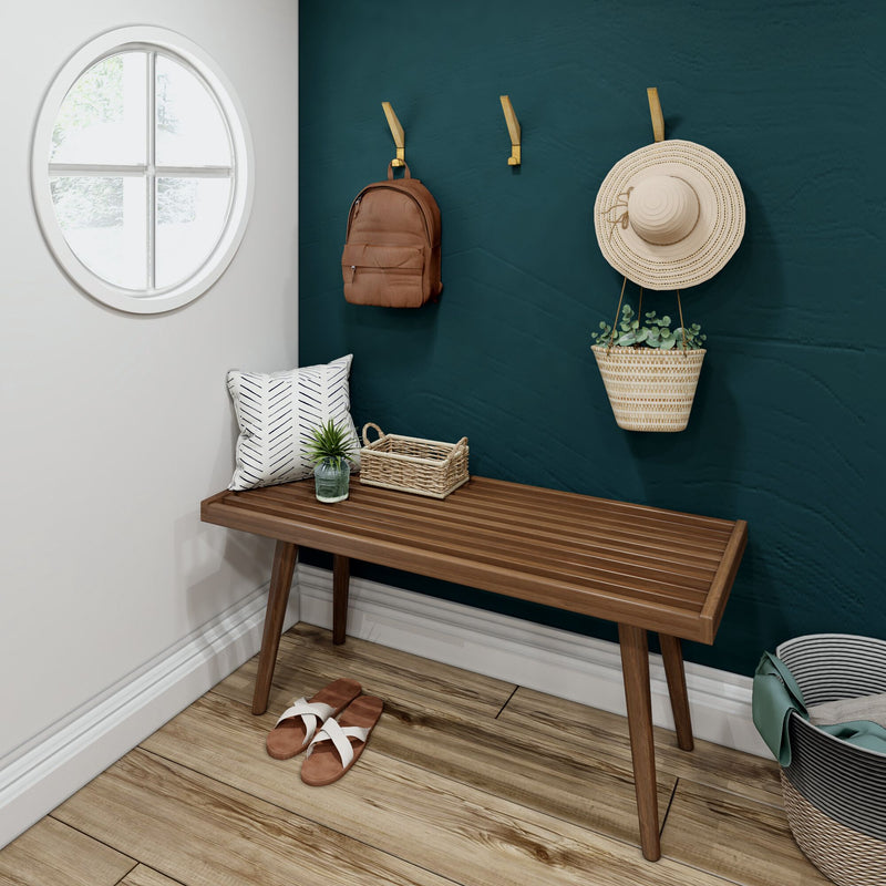 Minimalist entryway design with wooden bench, green accent wall, round window, hanging backpack, straw hat, and potted plant for stylish home decor.