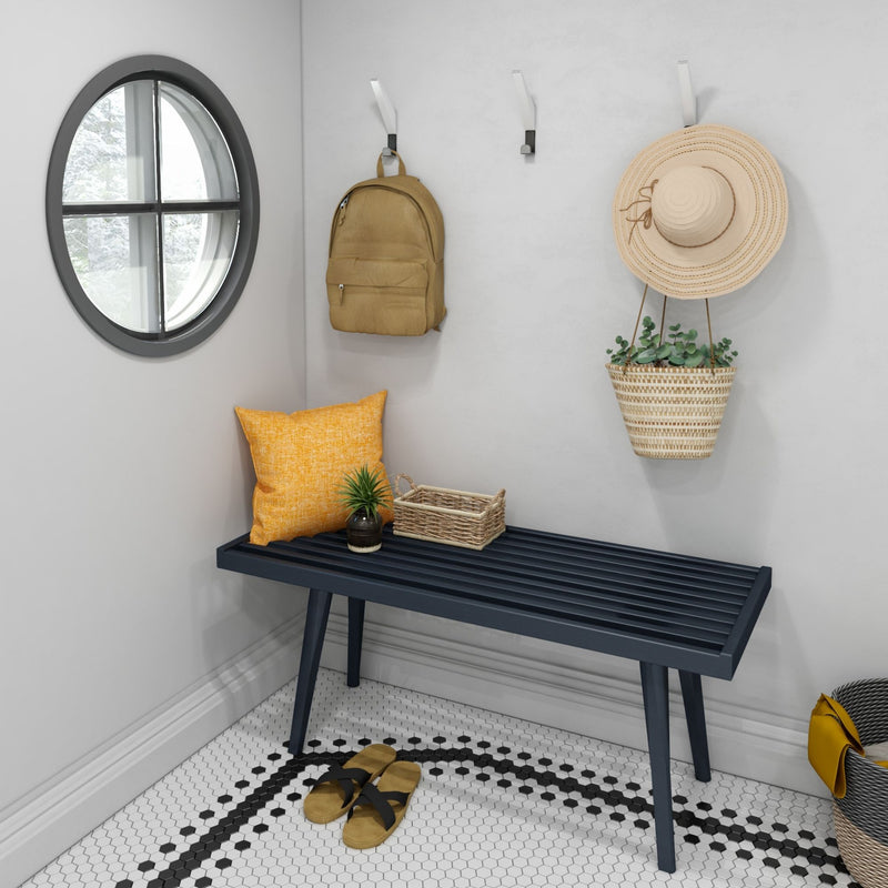Stylish entryway with modern bench, decorative pillow, backpack, hat, and hanging plant.