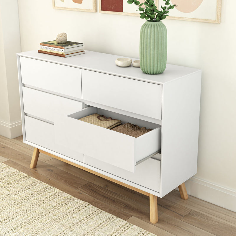 Mid-century modern white dresser with open drawer displaying folded clothes, green vase, and books on top for living room decor.