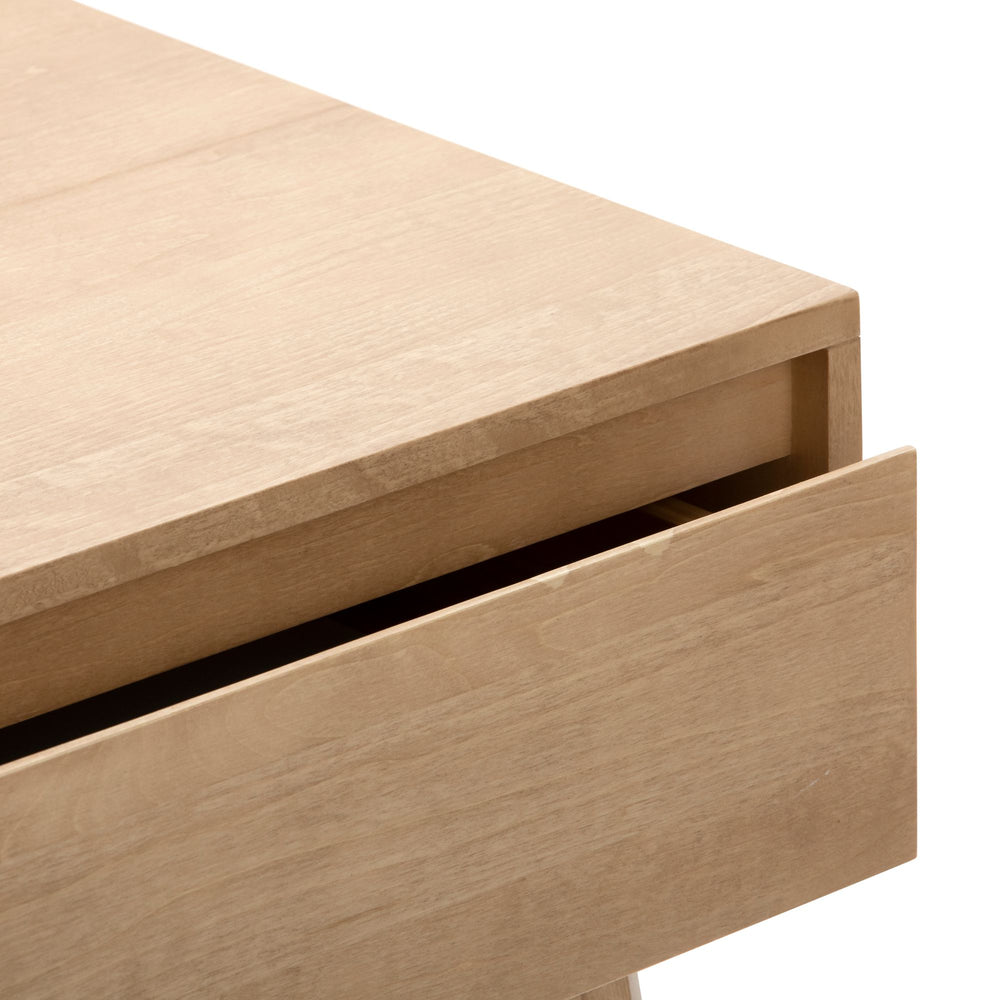 Natural wood desk corner with open drawer.
