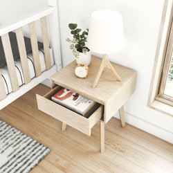 Modern wooden nightstand with open drawer, decorative lamp, clock, and vase in a cozy bedroom setting.