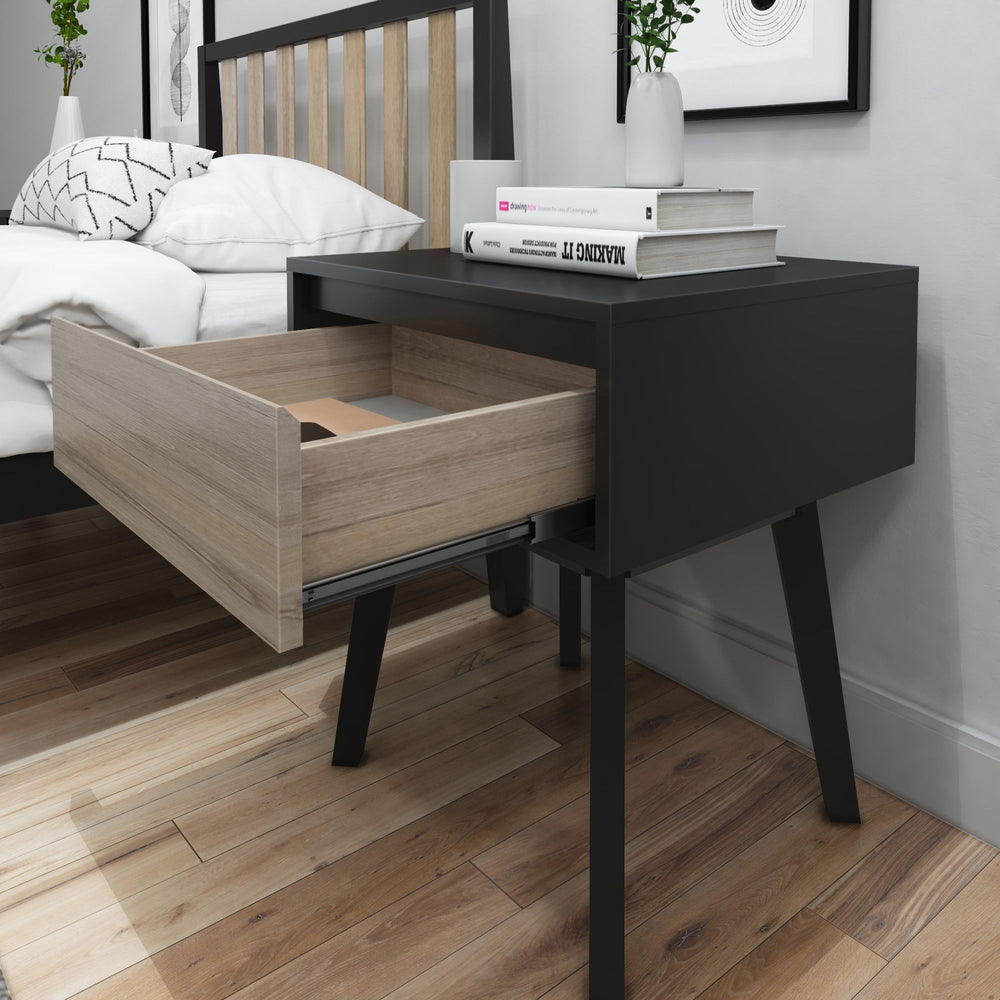 Modern black nightstand with open wooden drawer next to bed in stylish bedroom.