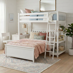 White twin-over-full loft bunk bed with ladder, built-in desk and shelves, pastel pink quilt and floral pillows in a bright coastal farmhouse kids’ bedroom with shiplap walls and potted plant