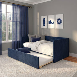 Navy blue upholstered daybed with pull-out trundle in modern bedroom, white bedding and accent pillows, sheer navy curtains, large window and framed skateboard wall art on gray walls.