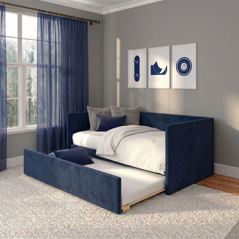 Navy blue upholstered daybed with pull-out trundle in modern bedroom, white bedding and accent pillows, sheer navy curtains, large window and framed skateboard wall art on gray walls.