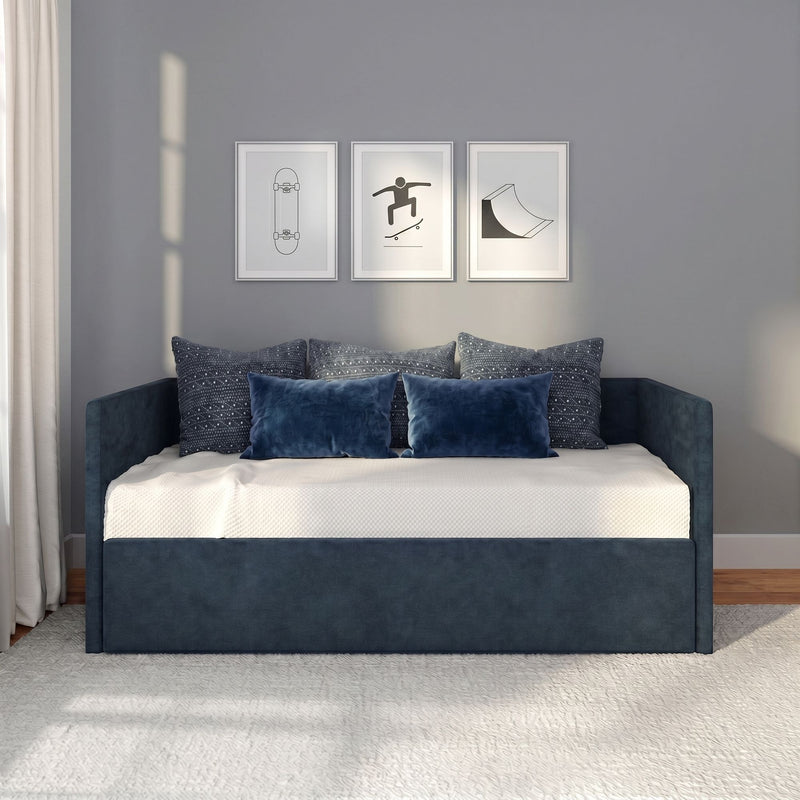 Modern bedroom with navy blue daybed and blue pillows beneath three minimalist skateboard-themed framed prints on gray wall.