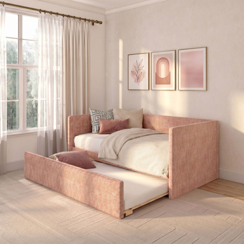 Sunlit modern blush pink daybed with pull-out trundle, neutral bedding and pillows, sheer curtains and minimalist framed wall art in cozy bedroom