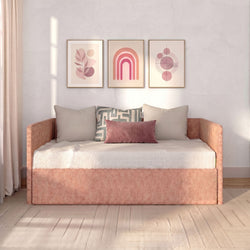 Modern boho living room daybed with blush-pink velvet pillow, geometric throw cushion, and three framed pink abstract art prints on a neutral wall in soft natural light
