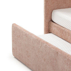 Close-up of blush pink upholstered platform bed frame with textured fabric headboard and footboard and white quilted mattress topper