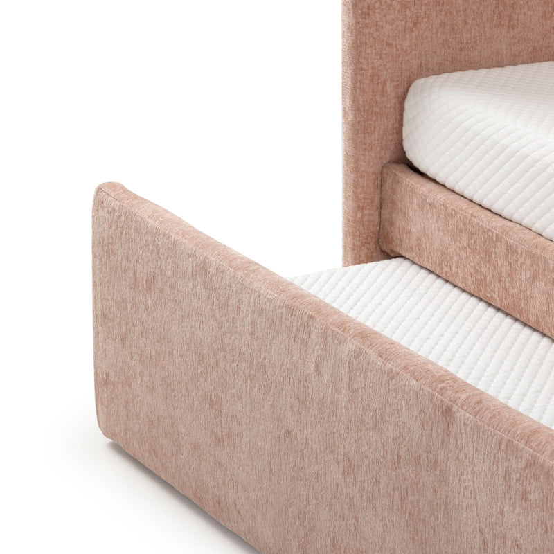 Close-up of blush pink upholstered platform bed frame with textured fabric headboard and footboard and white quilted mattress topper