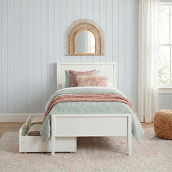 Cozy pastel twin bedroom with white storage bed, mint quilt, blush and faux-fur pillows, rattan sunburst mirror, shiplap wall and sheer curtains