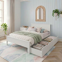 Sunlit Scandinavian bedroom with white storage bed and drawers, pastel bedding with green throw, hanging plants and arched rattan mirror on a light-blue shiplap wall