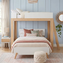 Modern kids bunk bed with natural wood frame and white panels, blush-pink bedding and textured beige throw, pastel blue paneled wall and rattan mirror