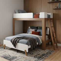 Modern wooden loft bunk bed with white guardrails and ladder, gray bedding and rust accent pillows in a kids' bedroom with wood-paneled wall and patterned area rug