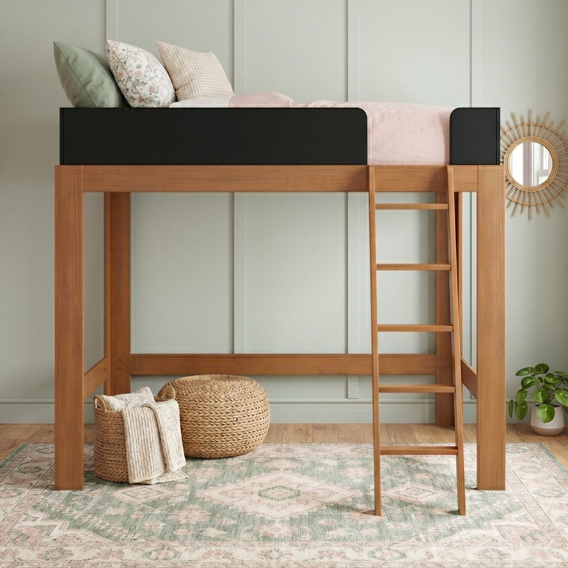 Kids' wooden loft bed with ladder and black guardrail, pastel pink bedding and floral pillows, boho woven pouf, patterned area rug and potted plant
