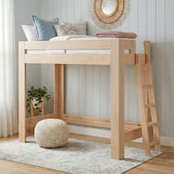 Natural wood loft bed with ladder in a neutral children's bedroom, styled with pastel pillows, rattan sunburst mirror, knitted pouf, potted plant and pastel rug