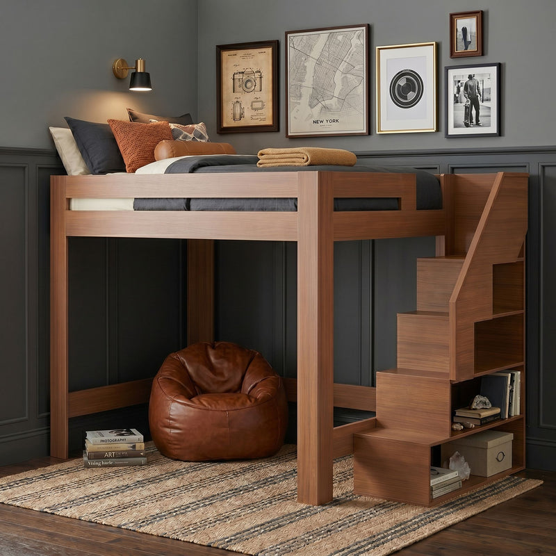 Modern wooden loft bed with built-in storage stairs, cozy reading nook with brown leather bean bag, textured rug, gallery wall and brass wall sconce on gray paneled walls